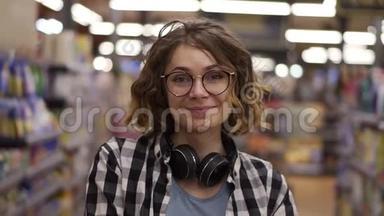 肖像年轻女子站在镜头前，微笑着在超市感受快乐的女孩购物脸<strong>零售店</strong>